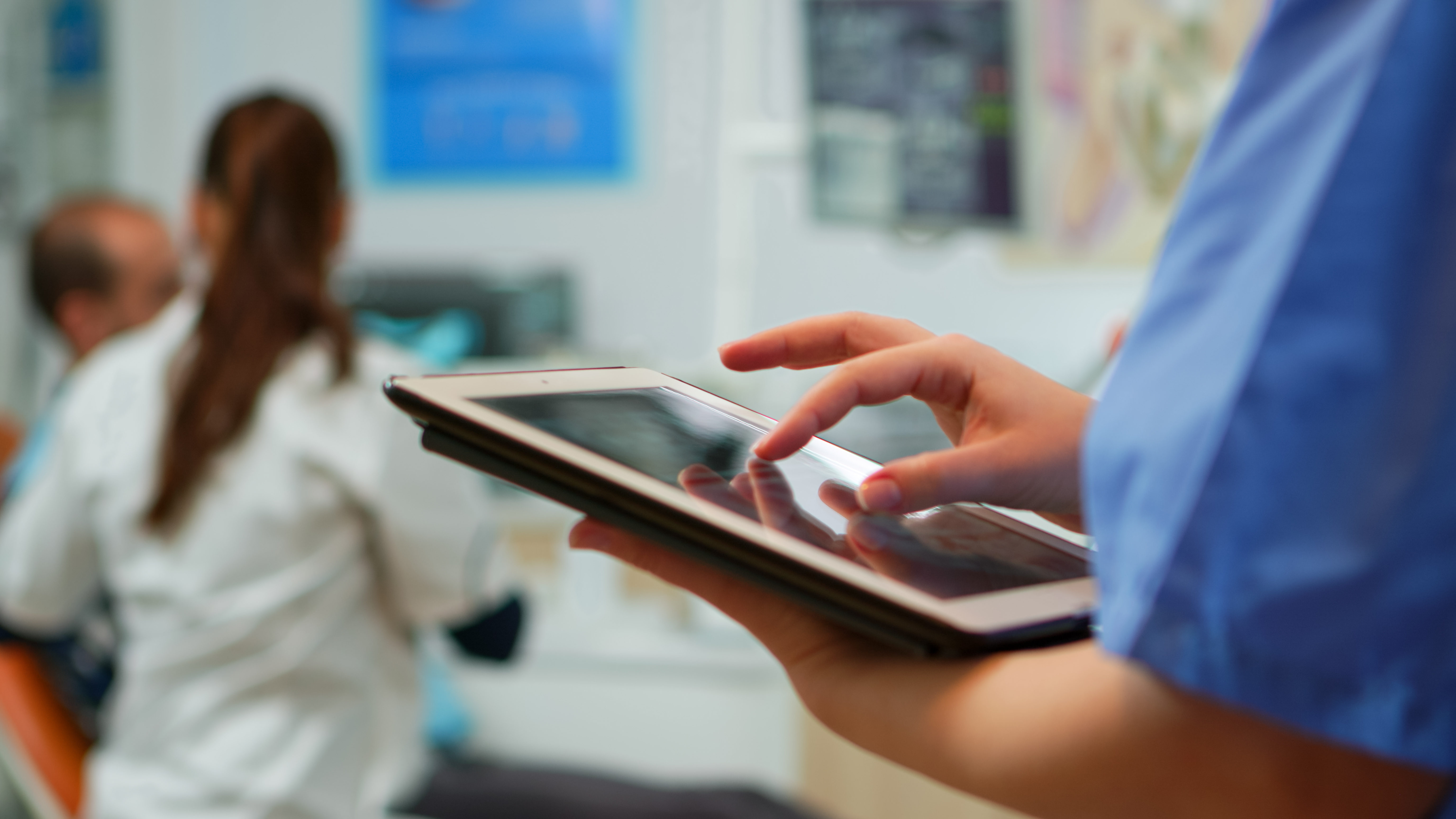 close-up-nurse-holding-typing-tablet-standing-stomatologic-clinic-while-doctor-is-working-with-patient-background-using-monitor-with-chroma-key-izolated-pc-key-mockup-pc-display