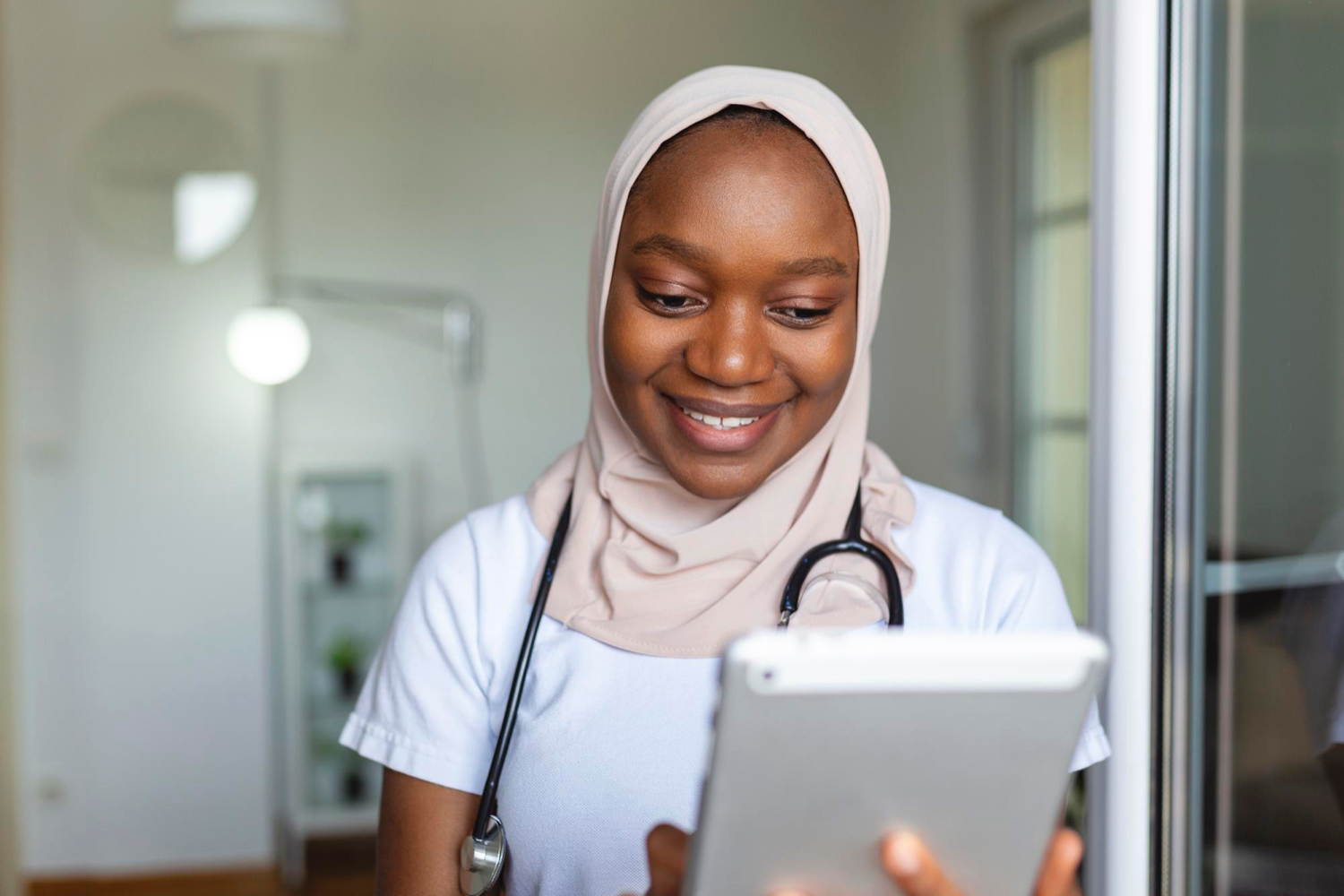 young-female-musllim-african-clinician-doctor-scrubs-using-touchpad-while-communicating-with-patients-online